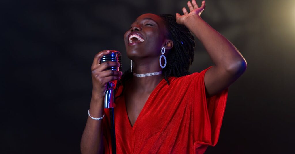 Energetic black female singer in red dress performing passionately on stage with a microphone.